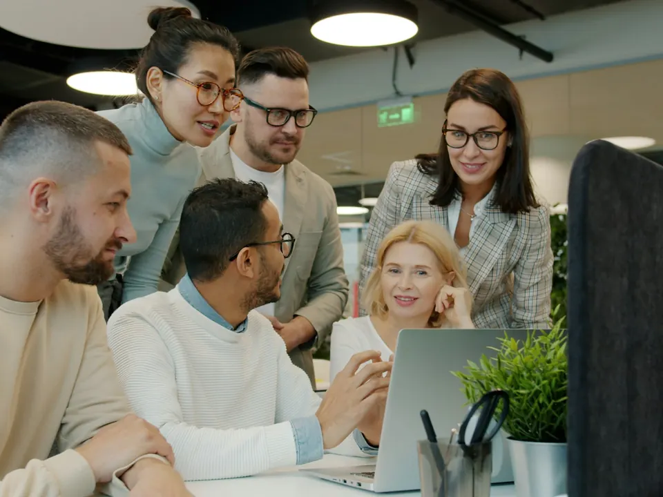 Ein Team bespricht sich gemeinsam vor einem Laptop