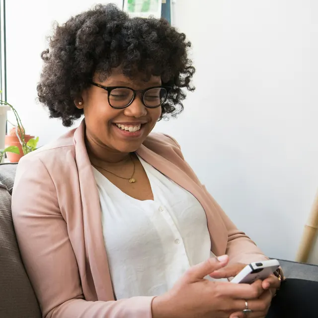 Eine Frau lächelt beim Blick auf ihr Smartphone
